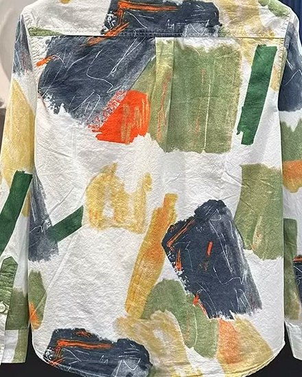 The brushstroke print across the back of the shirt: charcoal, moss green, ochre and burnt orange on ivory cotton.