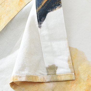 The hem and side seam in ivory and warm ochre.