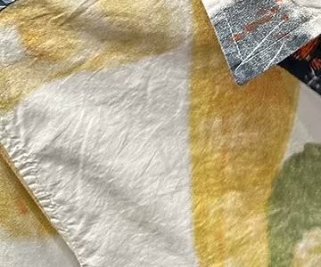 Macro view of the cotton surface: fine natural creases across ivory and ochre fabric.
